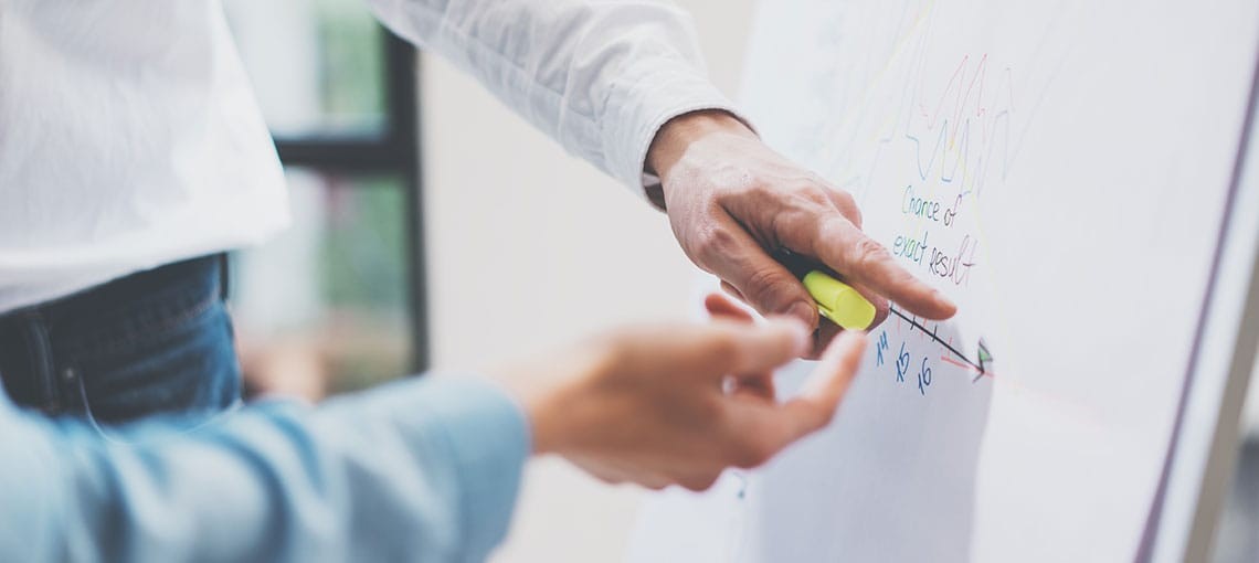 Zwei Hände die auf eine Grafik auf einem Flippchart-Blatt zeigen