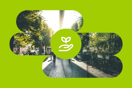 Stadtstraße mit Bäumen und Passanten, überlagert von einem grünen Kreis mit Hand-undPflanze-Symbol für den Leitbild-Wert Verantwortung.