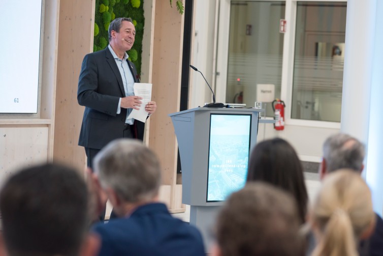 Bereichsleiter der Immobilien- und Stadtentwicklung, Andreas Tied, steht am Podium und refriert.