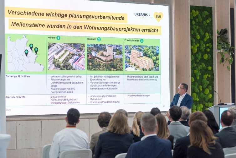 Vortragender beim Immobiliendialog 2025 mit PowerPoint-Präsentation im Hintergrund.
