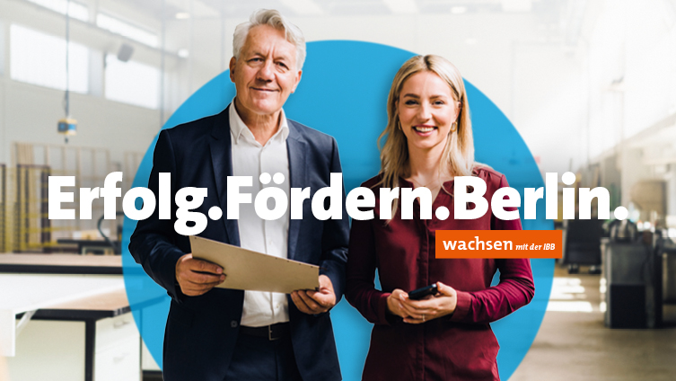 Ein Mann und eine Frau stehen in ihren Büroräumen mit Slogan: Erfolg.Fördern.Berlin.