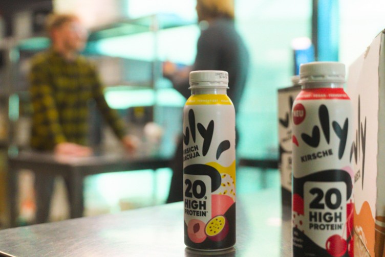 Zwei vly High-Protein-Drinks in den Sorten Pfirsich-Maracuja und Kirsche mit je 20g Protein, im Vordergrund auf einem Tisch